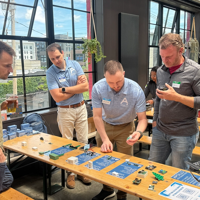 A few people gathering around a table demonstrating ESP32 hardware - Columbus, Ohio